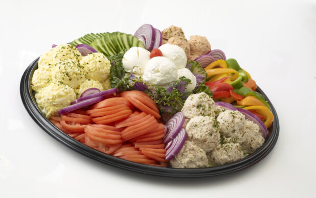 Dairy Platter with tuna salad, egg salad, salmon salad and cream cheese in mounds with sliced tomato, sliced cucumber, sliced red onions and slices of bell pepper all on a black catering tray