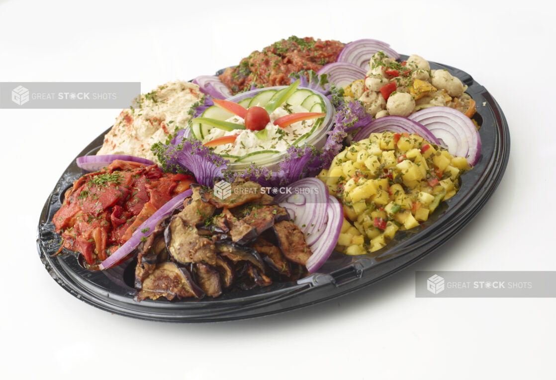 Mediterranean platter with roasted vegetables, roasted dips, hummus, marinated mushrooms and mango salsa on a round black catering tray