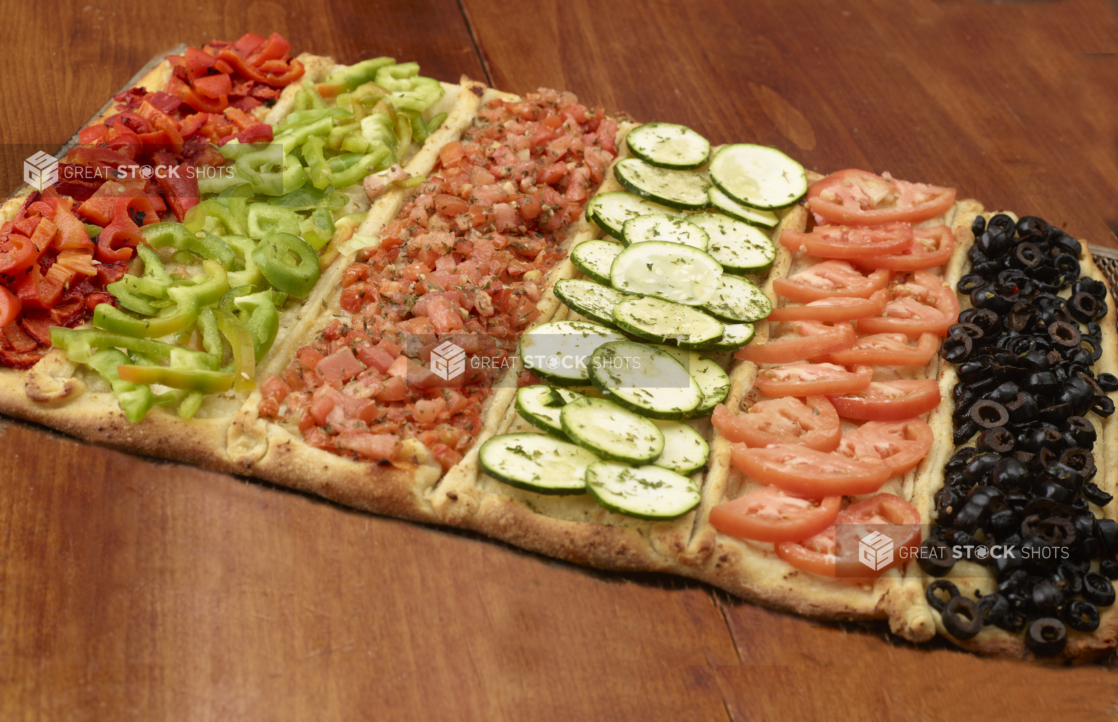 Flatbread Pizza with Assorted Fresh and Roasted Vegetable Toppings: Sliced Tomatoes, Black Olives, Bruchetta, Zucchini on a Wooden Table - Variation