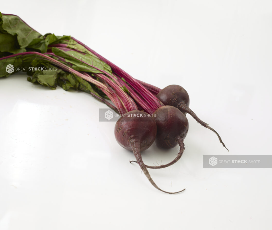 Bunch of whole fresh beets with the leaves on a white background