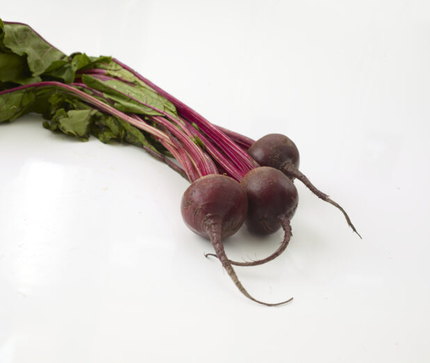 Bunch of whole fresh beets with the leaves on a white background