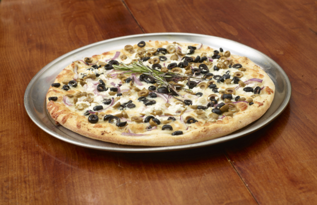 A Whole Mediterranean-Style Pizza with Red Onions, Feta Cheese and Olives on a Silver Platter on a Wooden Table