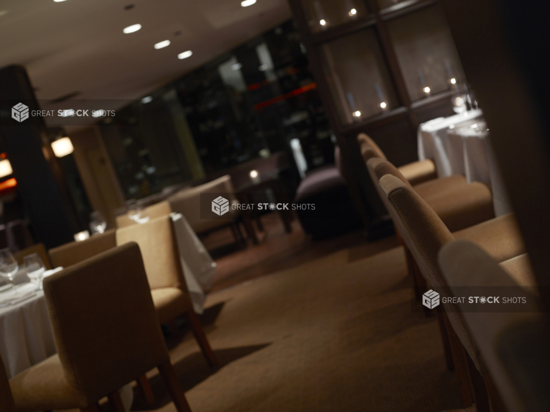 Interior of an elegant restaurant, tables set with white tablecloths and wine glasses, angled shot