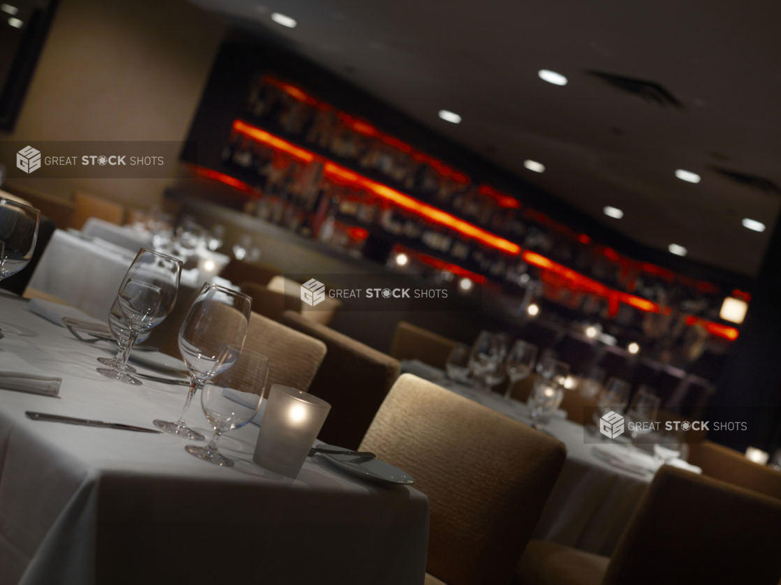 Interior of an elegant restaurant, tables set with white tablecloths and wine glasses, angled shot