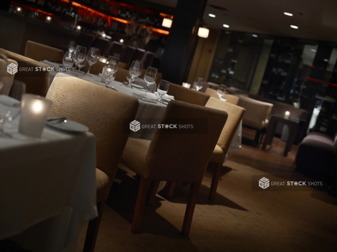 Interior of an elegant restaurant, tables set with white tablecloths and wine glasses, angled shot