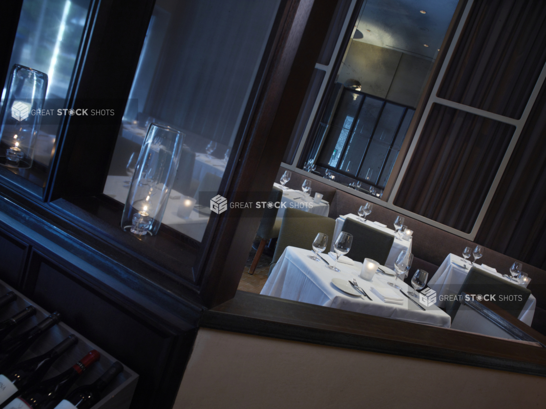 Interior of an elegant restaurant, tables set with white tablecloths and wine glasses, angled shot