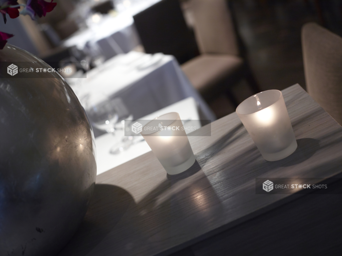 Interior of an elegant restaurant, tables set with white tablecloths and wine glasses, angled shot