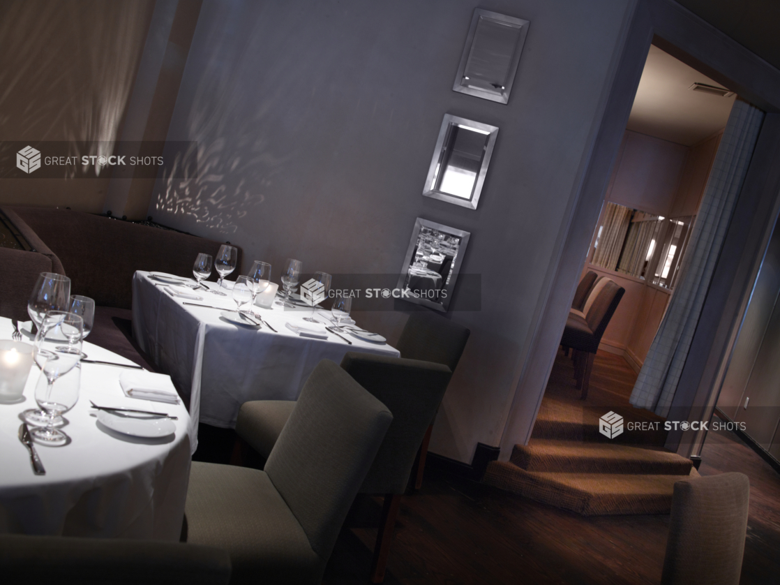 Interior of an elegant restaurant, tables set with white tablecloths and wine glasses, angled shot