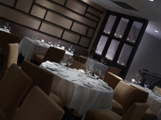 Interior of an elegant restaurant, tables set with white tablecloths and wine glasses, angled shot