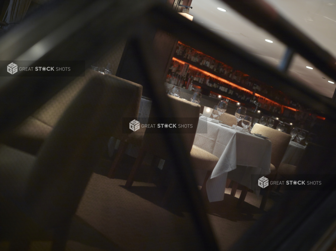 Interior of an elegant restaurant, tables set with white tablecloths and wine glasses, angled shot