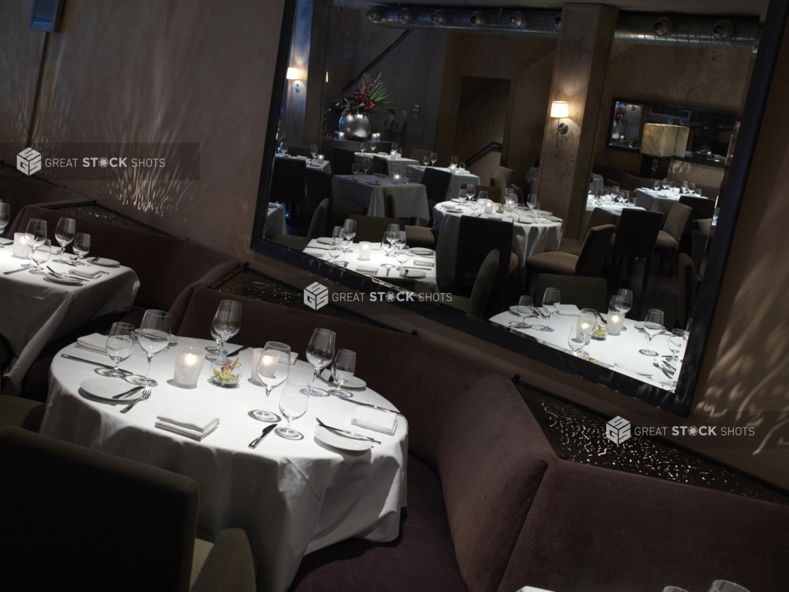 Interior of an elegant restaurant, tables set with white tablecloths and wine glasses, angled shot