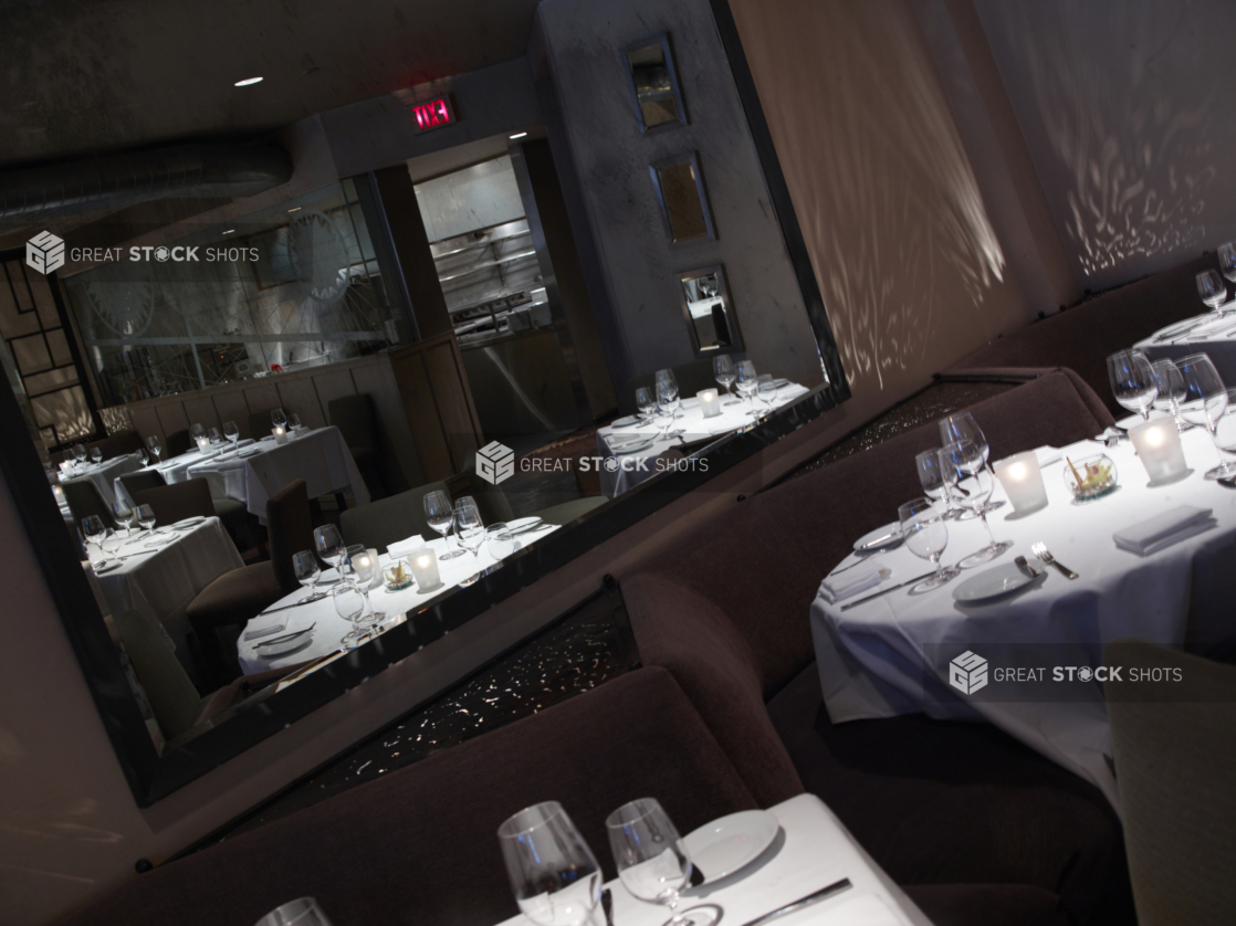 Interior of an elegant restaurant, tables set with white tablecloths and wine glasses, angled shot