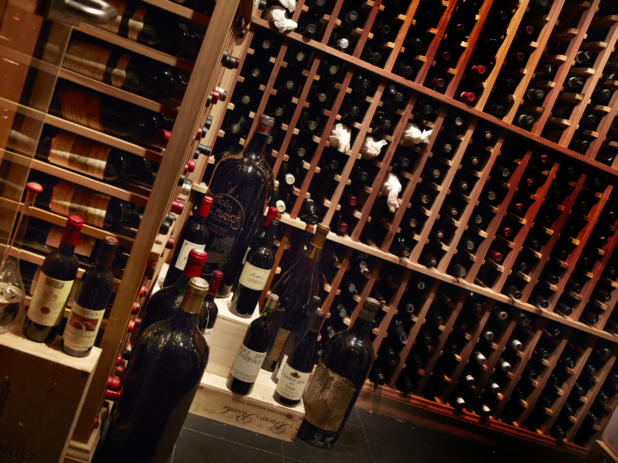 Wine rack in wine cellar, some bottles standing upright on floor, tilted angle