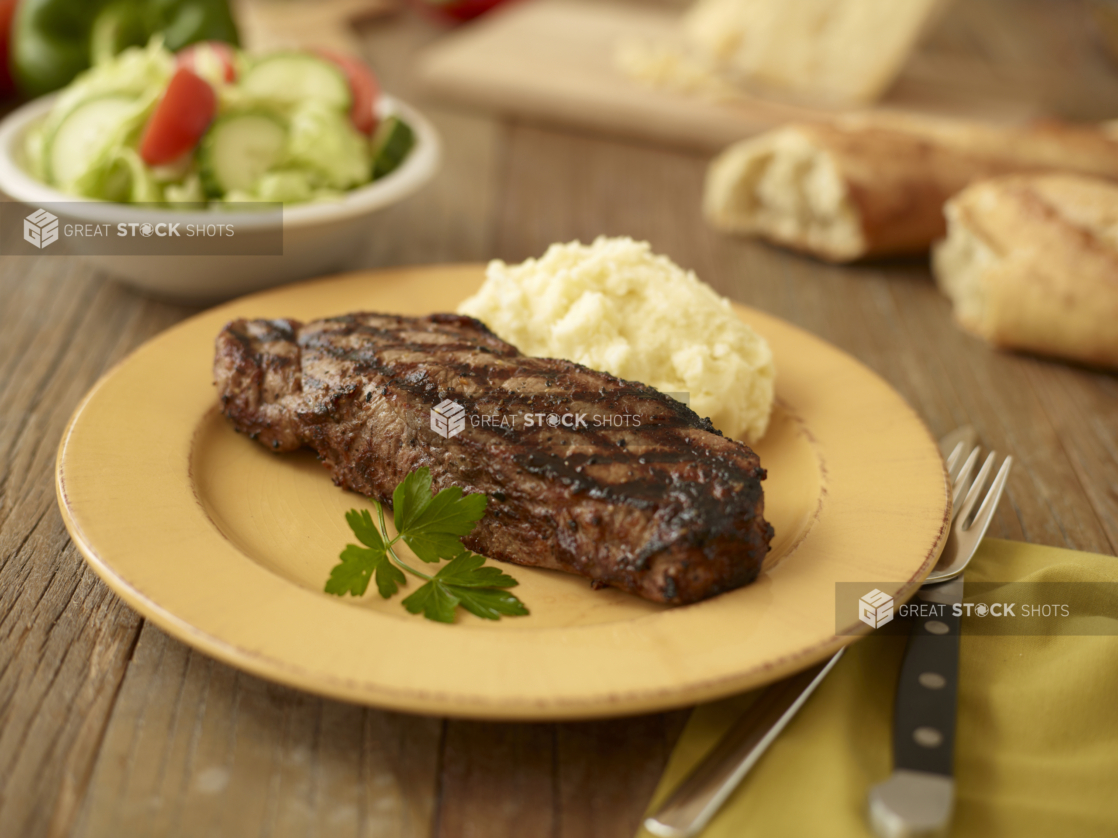 A grilled striploin steak with mashed potato on a plate