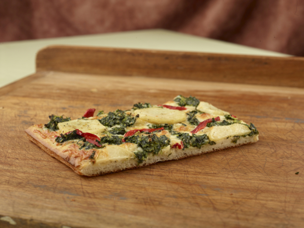 Close Up of a Slice of Sicilian-Style Rectangular Pizza with Potato, Spinach and Roasted Red Pepper Toppings on a Wooden Board