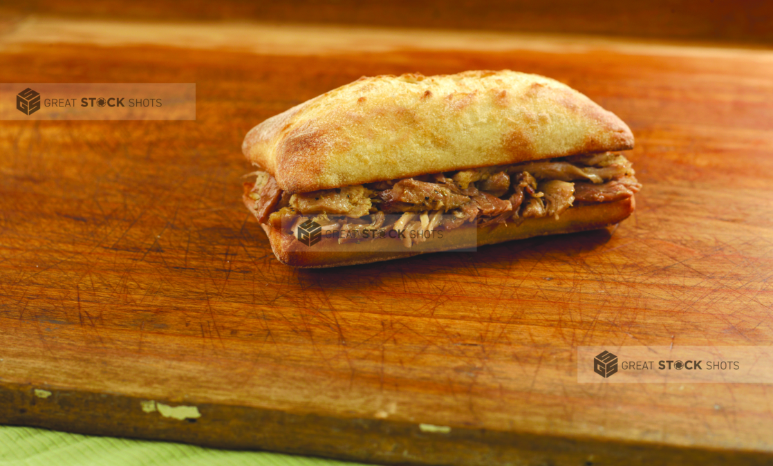 Pulled pork sandwich on a ciabatta bun on a wooden tabletop