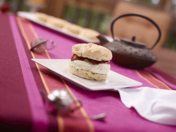Breakfast Biscuit Sandwich with Egg Whites and Bacon on a White Ceramic Dish on a Pink and Red Table Cloth Surface