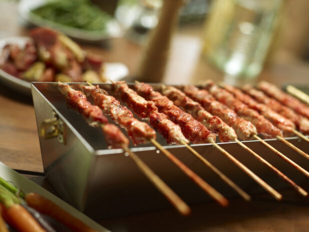 Chicken or Pork Satay Skewered Meat with a Spicy Sauce on a Kebab Grill Pan in an Indoor Setting