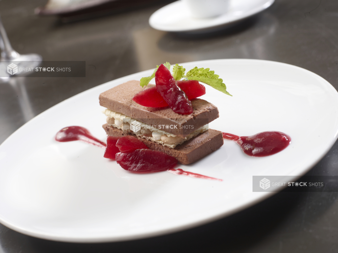 Chocolate Cake with a Berry Coulis on a White Ceramic Plate in a Fine Dining Setting