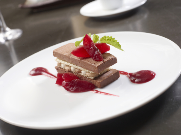 Chocolate Cake with a Berry Coulis on a White Ceramic Plate in a Fine Dining Setting