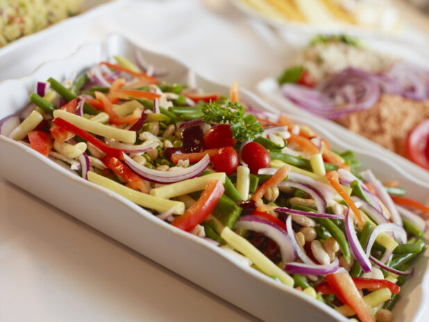 Cold vegetable salad in a white rectangular serving dish, close-up, tilted angle