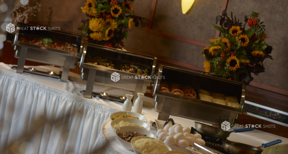 Breakfast buffet table with steamers full of hot food at a catered event