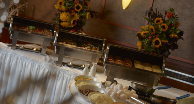 Breakfast buffet table with steamers full of hot food at a catered event