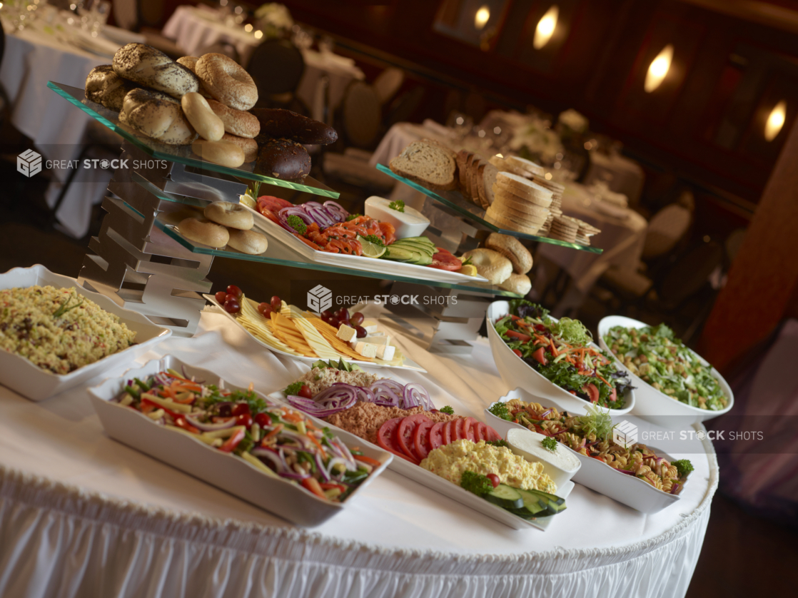 Buffet table at a catered event with dairy platter, lox platter, cheese platter and pasta and other cold salads