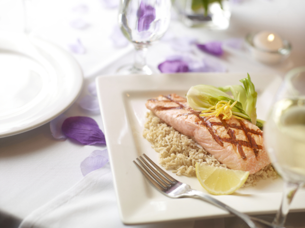 Grilled salmon on rice with a wedge of lemon on a square white plate, spring colours