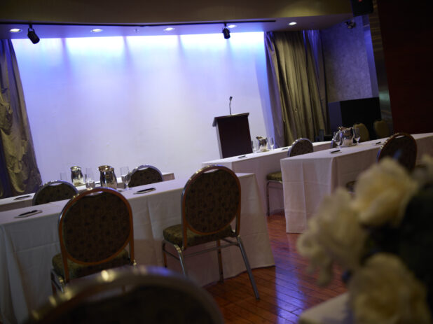 point of view perspective of an even space set up for a speaker with note pads and pens at the each seat