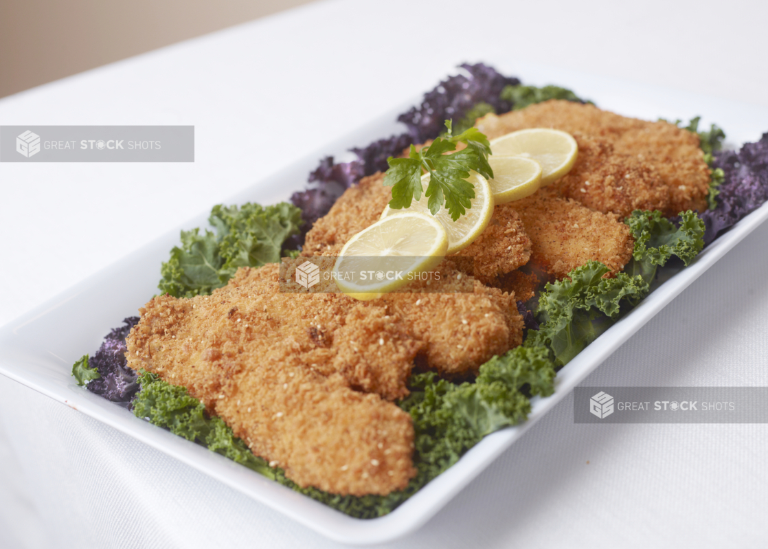 a catering tray of chicken fingers with sliced lemons