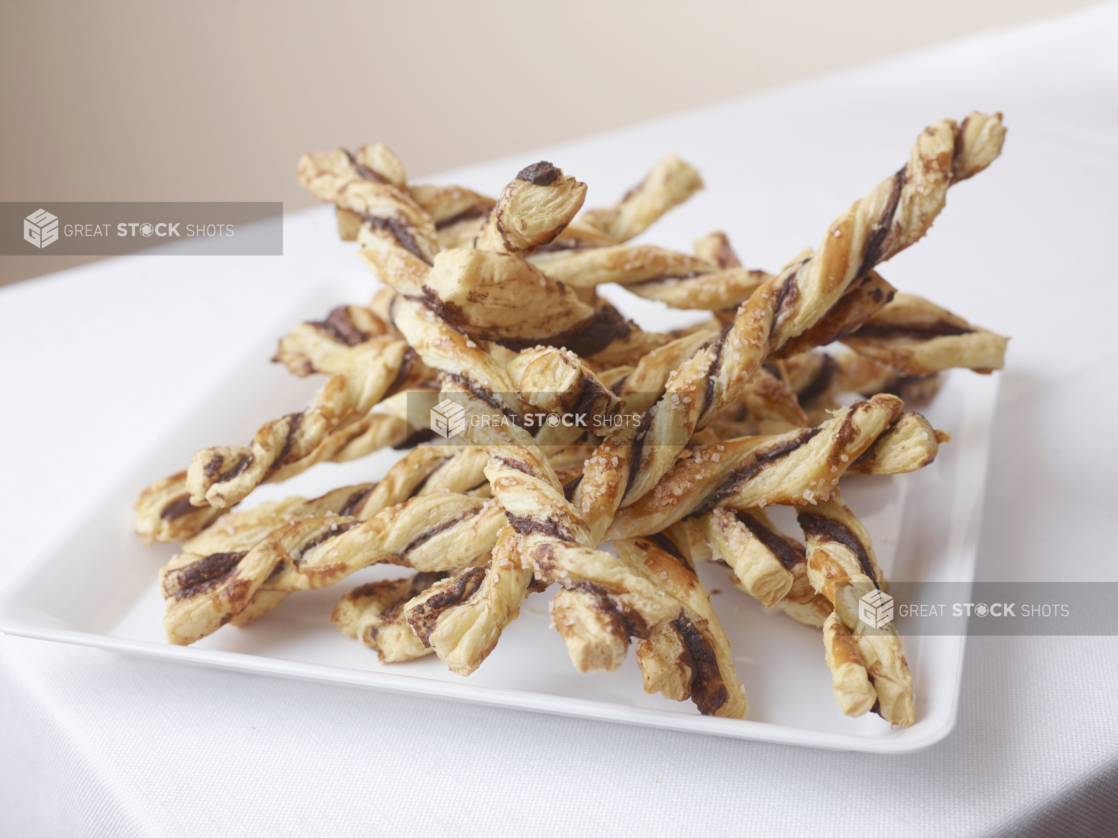 pile of spiral twisty bread sticks on a white tray