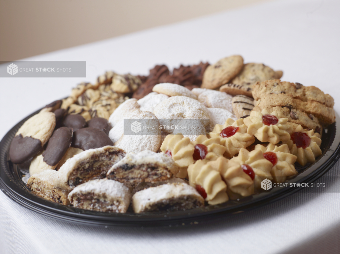 Close Up of a black plastic party platter of italian style cookies on a white table cloth