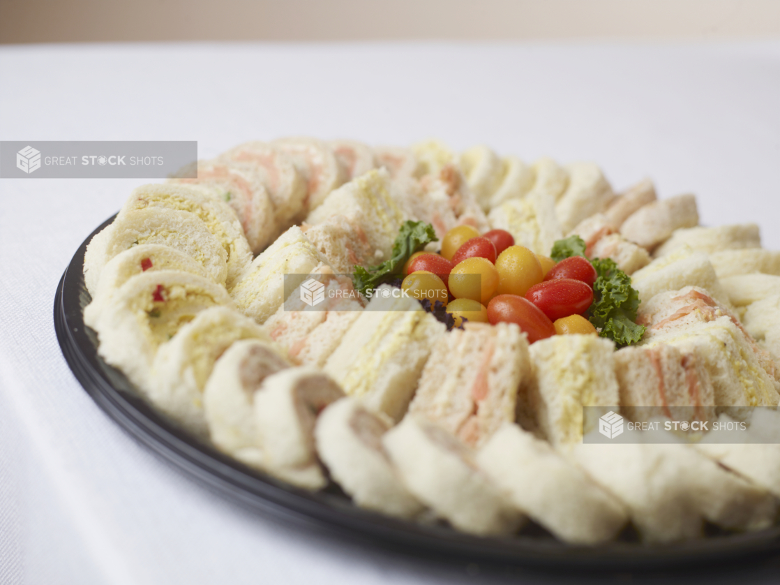 round platter of assorted party sandwiches on a white surface