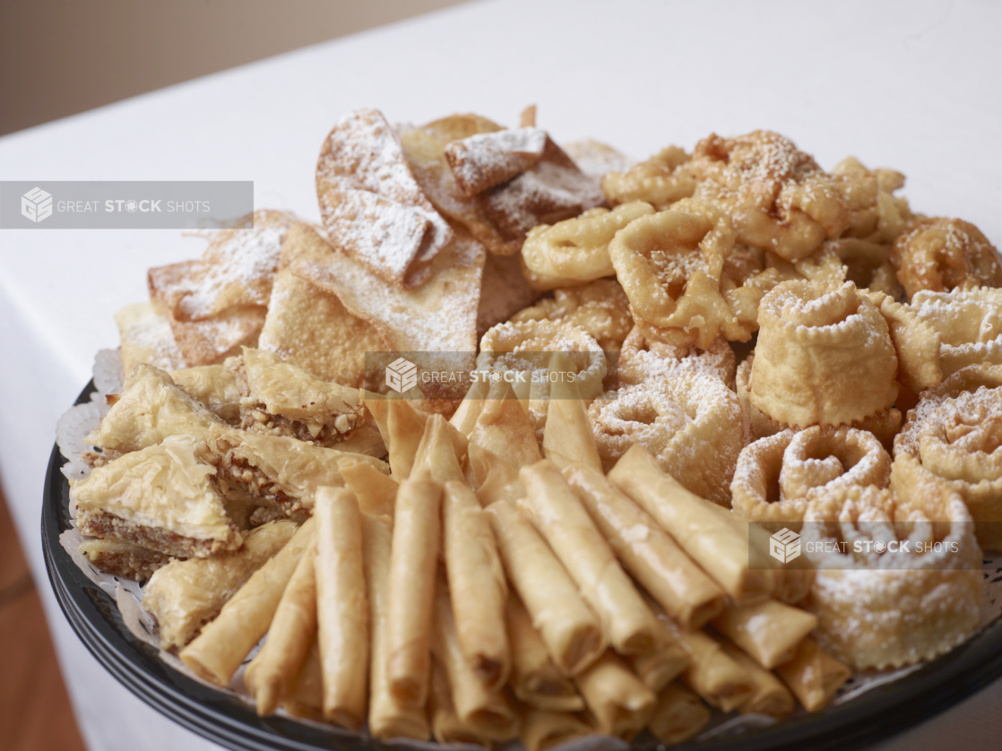 A black plastic platter with fried dough desserts covered with powdered sugar