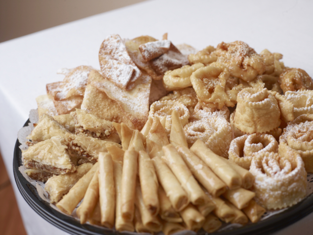 A black plastic platter with fried dough desserts covered with powdered sugar