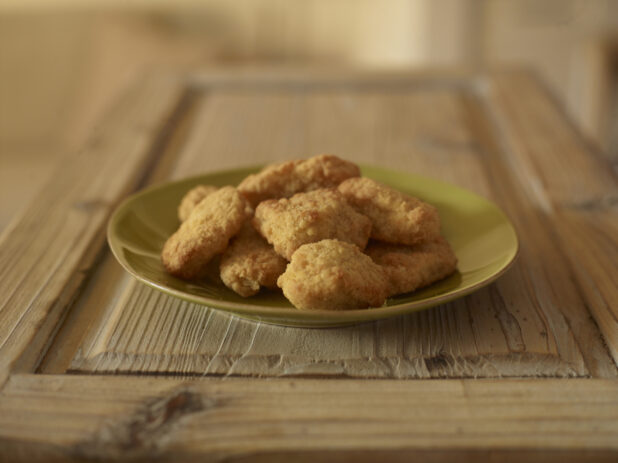 Chicken nuggets on a green plate on a rustic wood surface