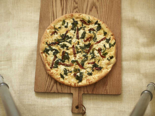 Whole unsliced white pizza with spinach, goat cheese, and roasted red peppers