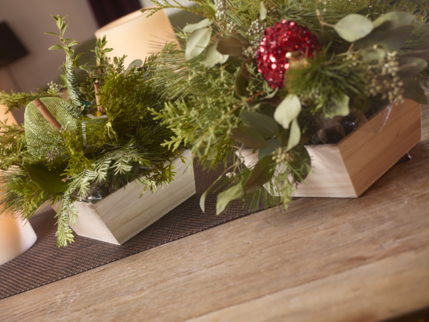 Table decorated for Christmas with greenery arrangements in wood catering trays