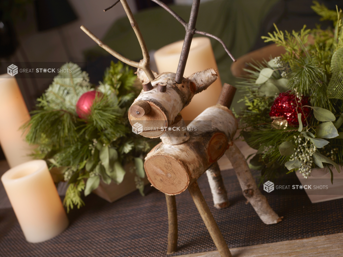 Table decorated for Christmas with reindeer folk art, greenery arrangements in wood catering trays, and candles