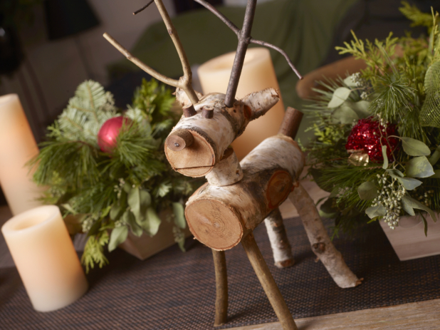 Table decorated for Christmas with reindeer folk art, greenery arrangements in wood catering trays, and candles