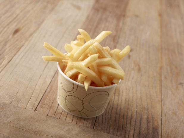 Thick Cut Plain French Fries in a Paper Take-Out Bowl on a Weathered Wooden Surface in an Indoor Setting