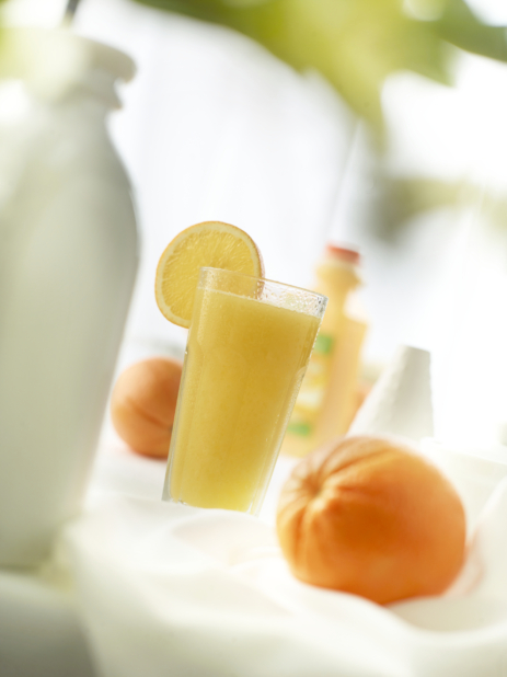 A glass of freshly-squeezed orange juice with fresh oranges on white, bokeh