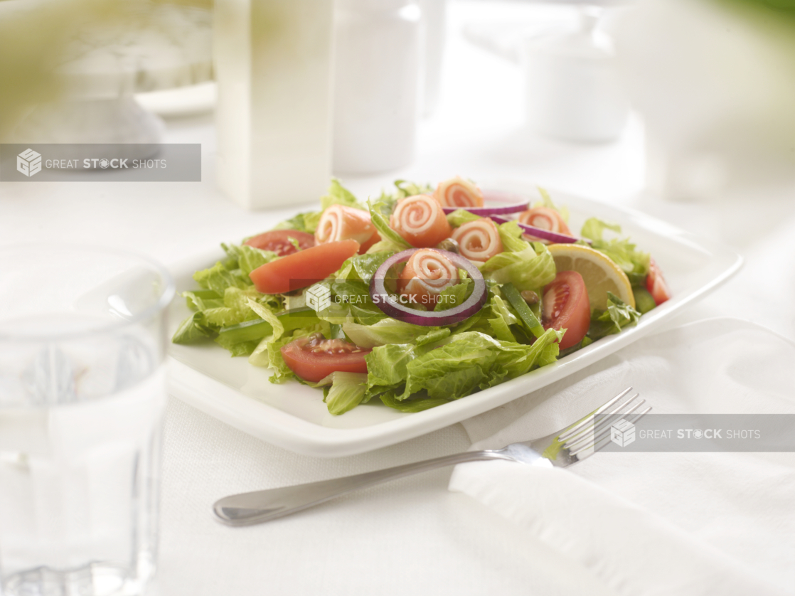 Romaine salad with rolled UNKNOWN in an all-white table setting