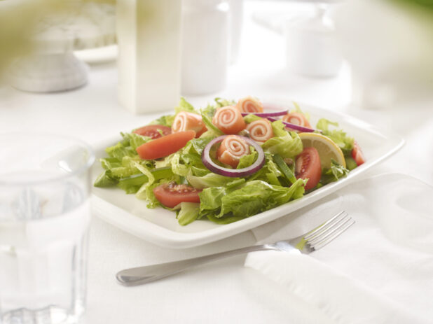 Romaine salad with rolled UNKNOWN in an all-white table setting