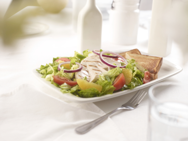 California-style romaine salad with grilled chicken, red onions, oranges, and tomato wedges with white toast on the side, white table setting