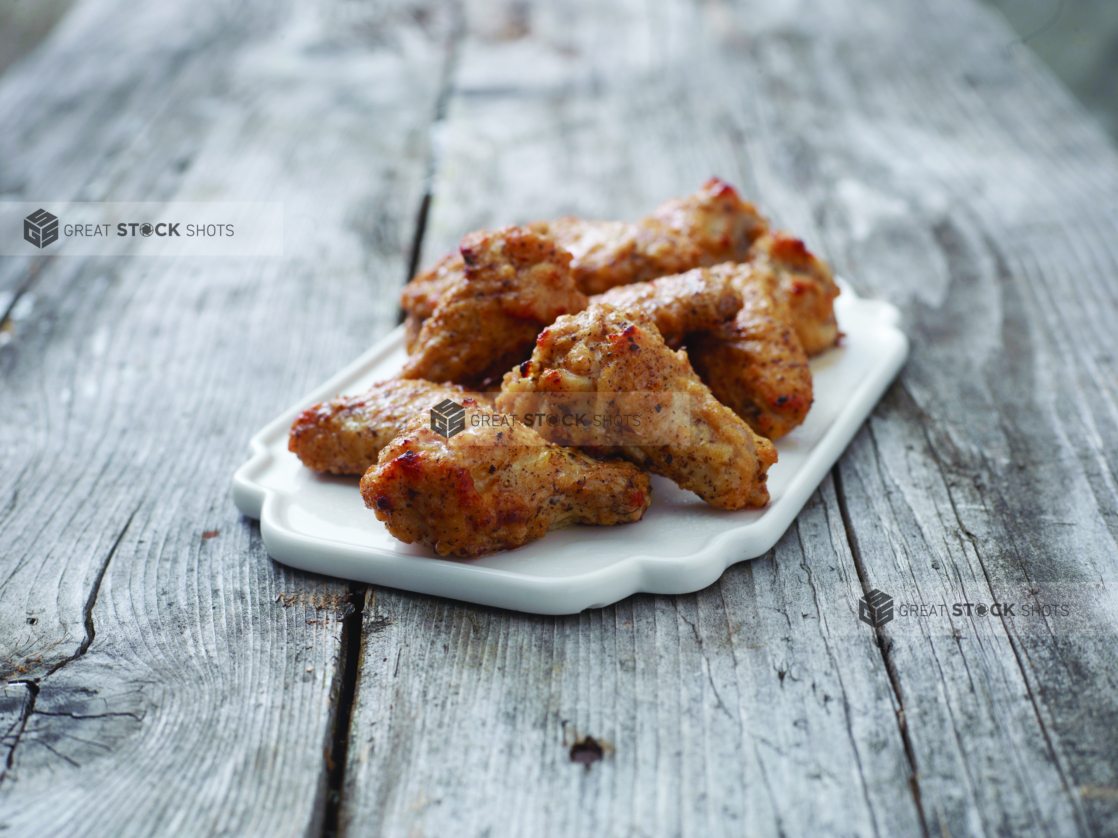 A Close Up of a Dish of Oven-roasted Chicken Wings on a Weathered Wooden Table