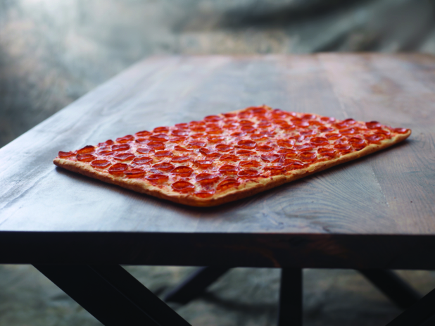 A Large Party-sized Pepperoni Pizza on a Dark Wooden Table Against a Brown Canvas Background
