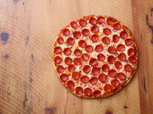 Overhead View of a Whole New York Style Pepperoni Pizza on a Two Tone Wooden Table