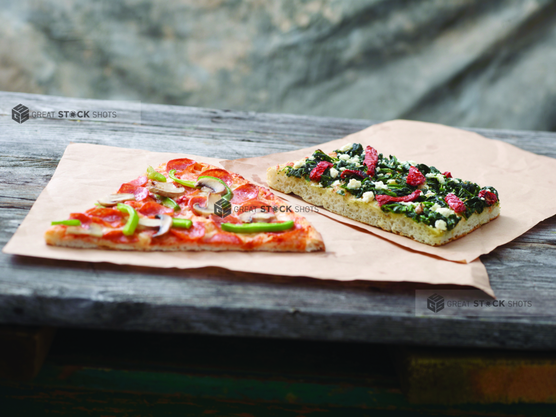 Jumbo Deluxe Pizza Slice and Romano Pizza al Taglio Slice on Kraft Paper on a Weathered Wooden Table – Variation 2